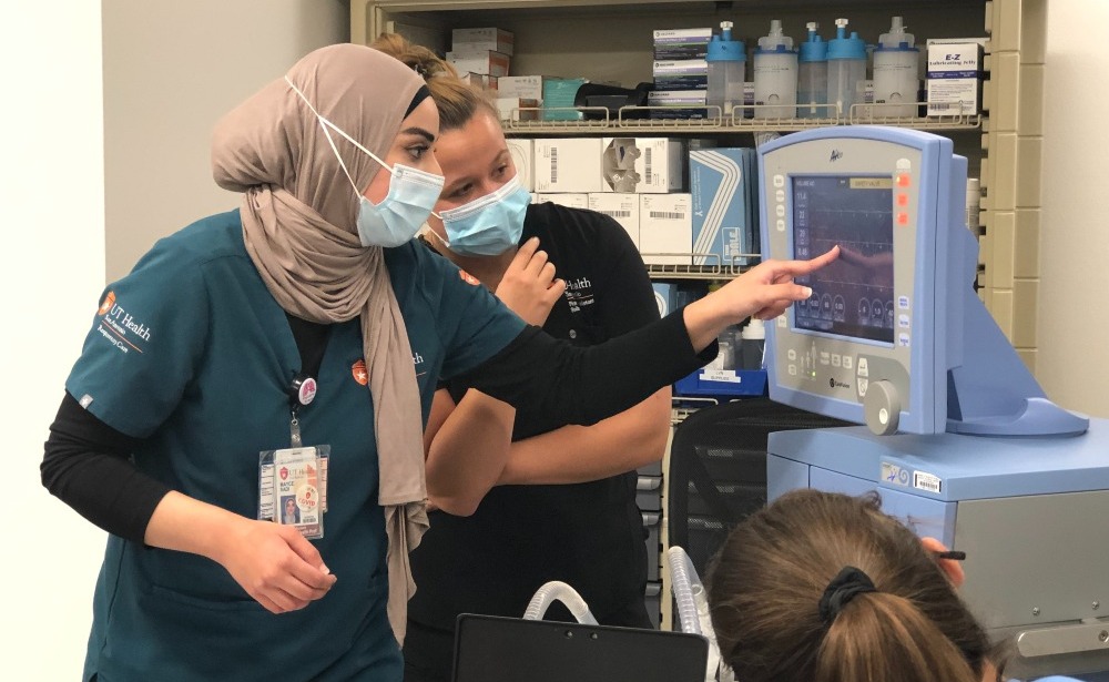 Respiratory Care student Mayce Sadi shows PA Studies student Bryce Holmgren and other PA students how to use a mechanical ventilator.