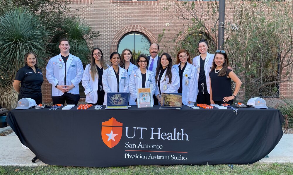 PA Studies students, School of Health Professions Dean David Shelledy and PA faculty pose in front of table promoting PA Studies at the newly dedicated UT Center at Laredo.